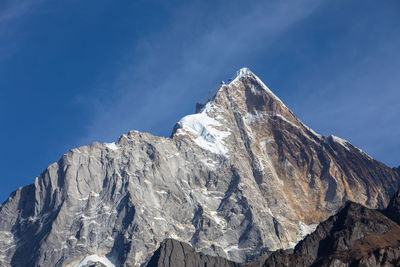 Low angle view of snowcapped mountain against blue sky