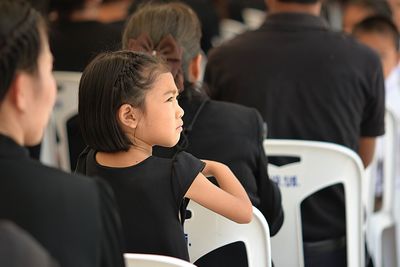 Rear view of girl looking away while sitting on chair