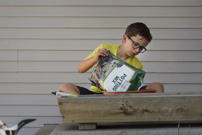 Boy mixing fertilizer in flower pot at backyard