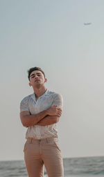 Young man looking at sea against sky