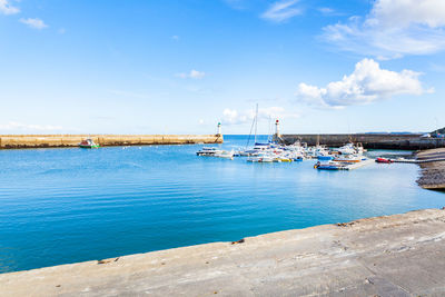 Boats moored in sea against blue sky