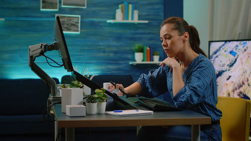 Side view of woman using mobile phone while sitting on table