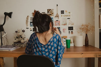 Rear view of young woman sitting at home