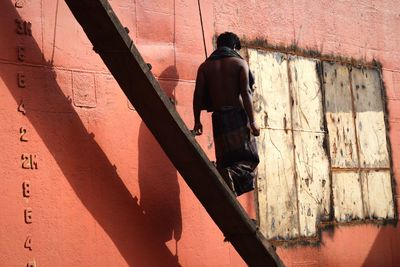 Rear view of man moving down on staircase by wall