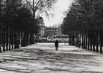Rear view of man walking on footpath in city