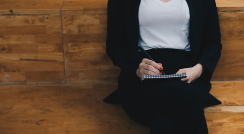 Midsection of woman holding umbrella while standing on table