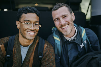 Portrait of happy male friends sitting in van trunk