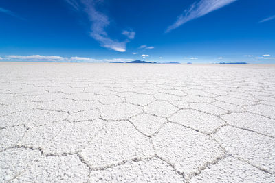 Surface level of barren landscape against blue sky