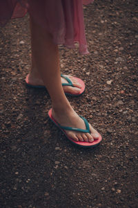 Low section of woman standing on pebbles in city