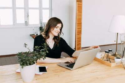 Young woman using phone while sitting on table