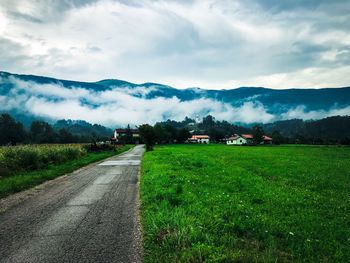 Road amidst field against sky