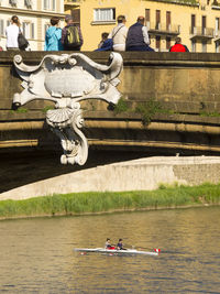 People at ponte santa trinita bridge against buildings