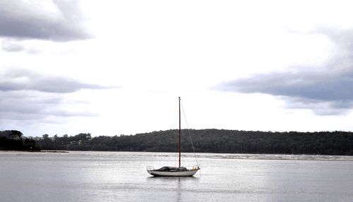 Boat in shallow water against cloudy sky