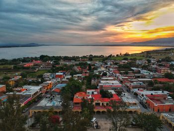 High angle view of townscape by sea against sky during sunset