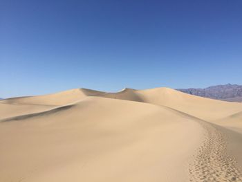 Scenic view of desert against clear blue sky