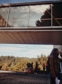 People against sky seen through window