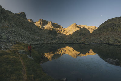 A young man with backpack looking at lake reflection, sierra de gredos