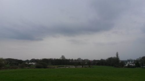 View of grassy field against cloudy sky