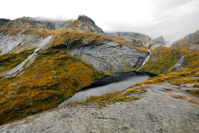 Panoramic view from mountain summit of waterfall and lake in valley in moskenesoya lofoten norway