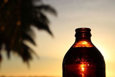 Close-up of beer bottle against sunset