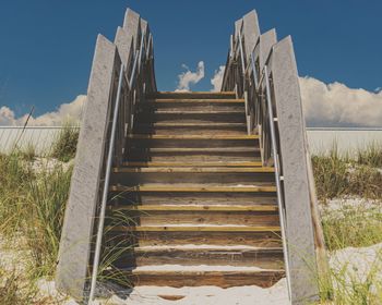 Low angle view of steps leading towards beach against sky