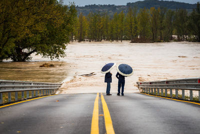 Rear view of a man with umbrella on road