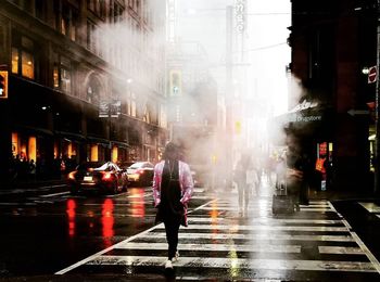 People walking on wet road in city during rainy season