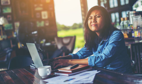 Young woman using phone while sitting on table