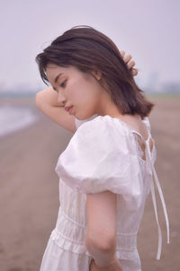 Young woman looking away while standing on land