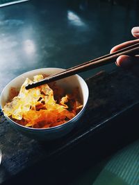 Cropped hand of person having food in bowl on table