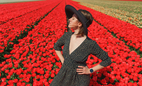 Full length of woman standing by red flowering plants