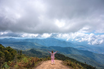 Rear view of man standing on mountain against sky