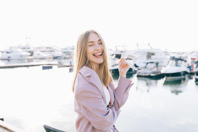 Portrait of smiling young woman standing against river