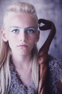 Close-up portrait of boy with long blond hair and eye make-up