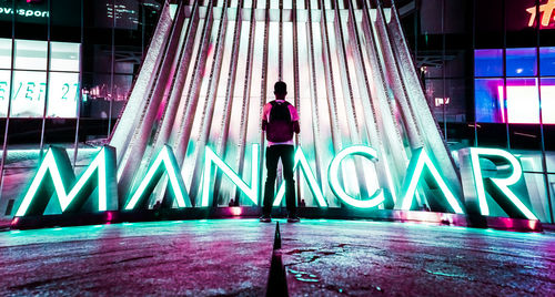 Full length of woman standing on illuminated bridge in city at night