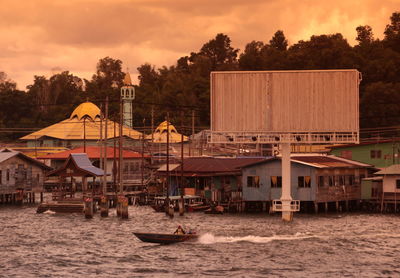 Stilt houses over river against trees