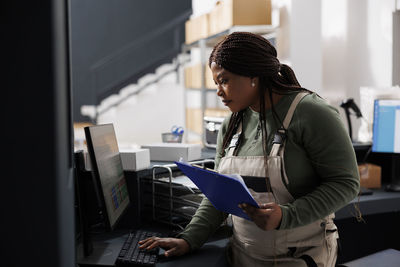 Side view of man using laptop while standing in office