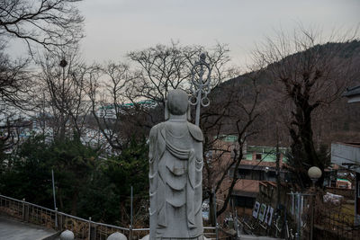 Statue by trees against sky