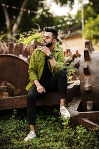 Young man looking away while sitting on land