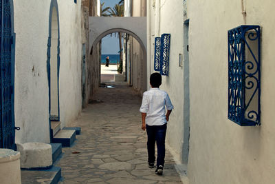 Rear view of boy walking by building