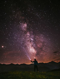 Rear view of man standing against star field at night