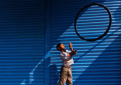 Full length of man standing against blue wall