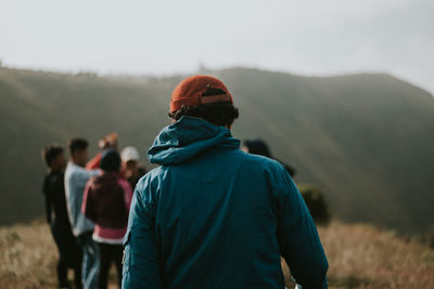 Rear view of people on field against mountain