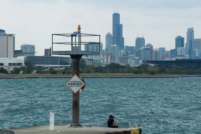 Rear view of woman standing by sea against sky