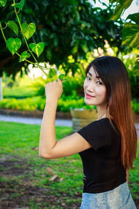 Portrait of smiling young woman against plants