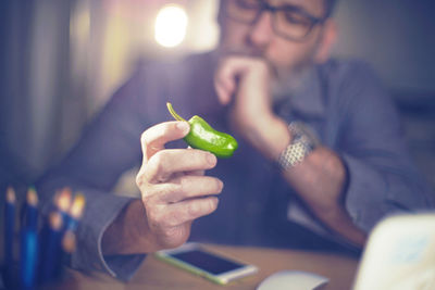 Close-up of man looking at chili pepper