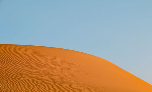 Low angle view of sand dunes against clear sky