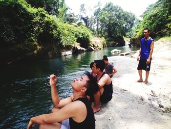 People enjoying in lake against trees