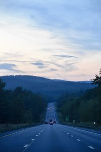 Road amidst trees against sky during sunset