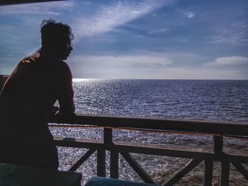 Rear view of man looking at sea against sky